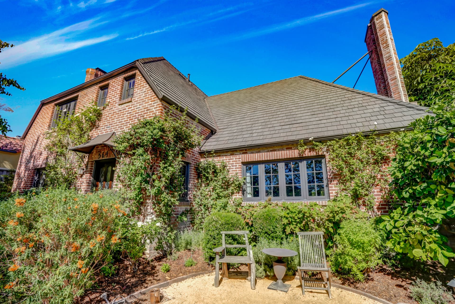 Hancock Park brick cottage exterior with climbing vines and garden seating