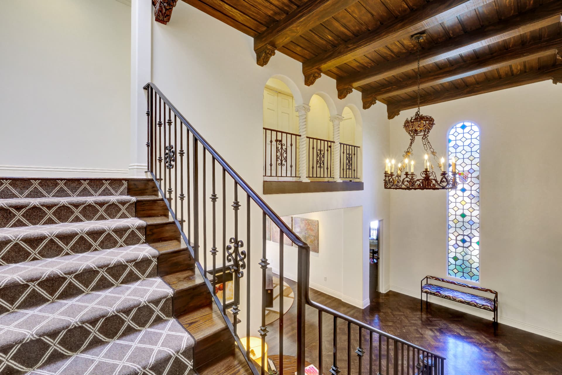 Hancock Park sweeping staircase with wrought iron railing and wood beams